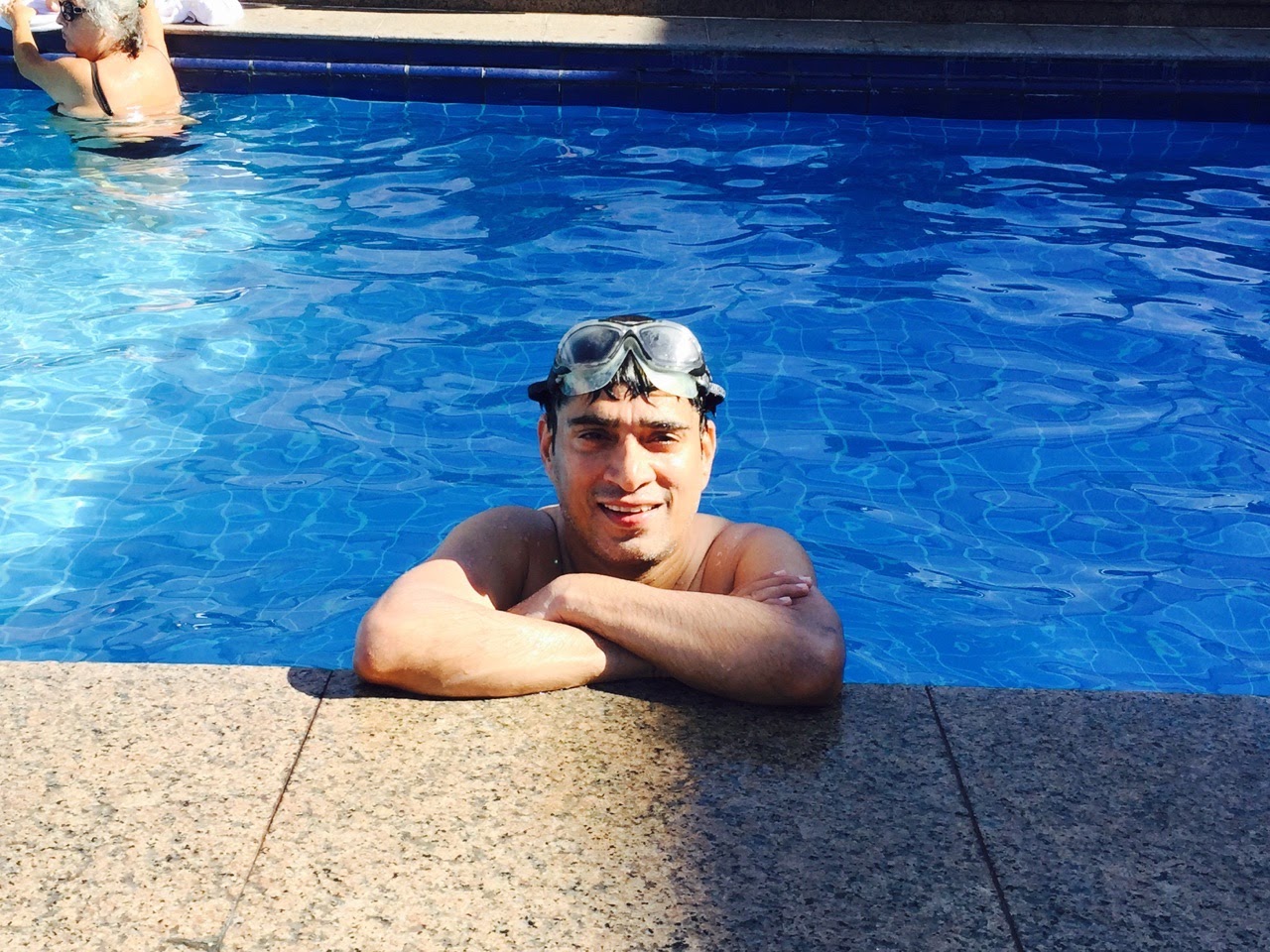 Kunwer Sachdev resting at the pool edge with goggles after a swim