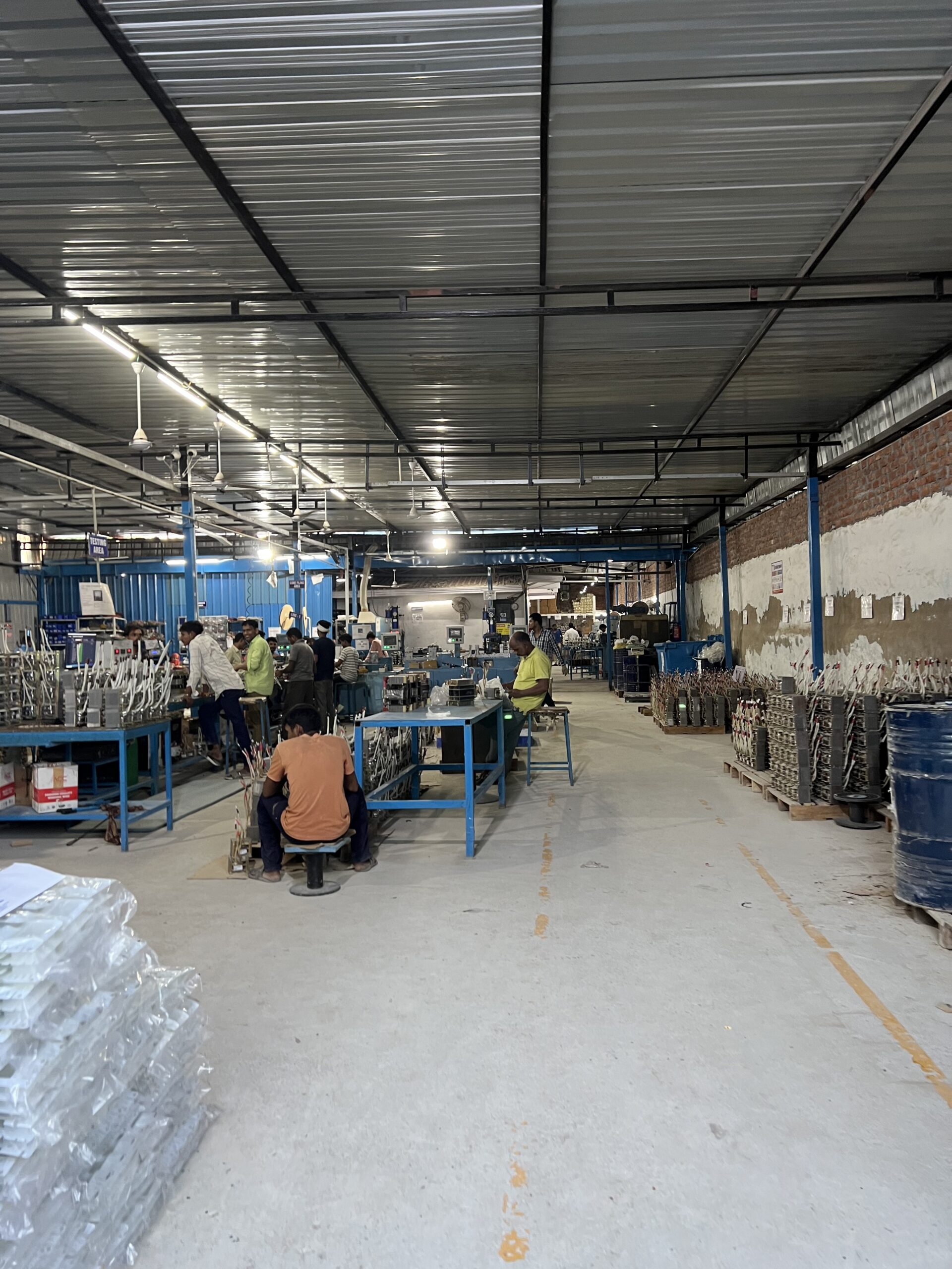 Shop-floor hardware assembly line with workers at benches and power modules under testing