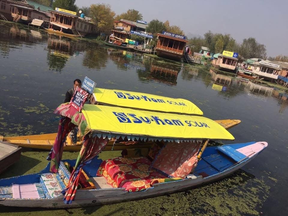 Two Kashmiri shikaras with yellow Su-Kam Solar canopies on Dal Lake