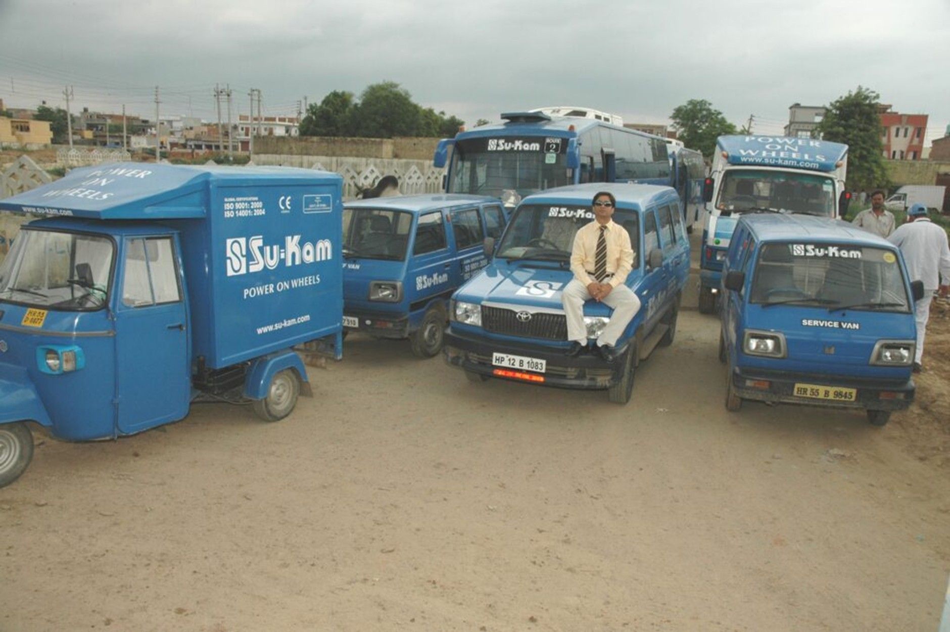 Su-Kam Power On Wheels fleet with Kunwer Sachdev — demo truck, service vans, three-wheeler and branded vehicles on dusty ground